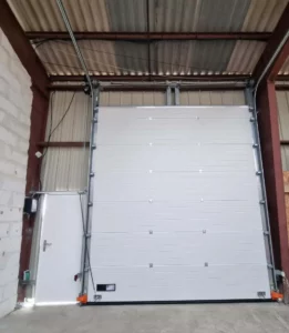 Porte sectionnelle et porte piétonne Grande porte sectionnelle blanche et petite porte piétons